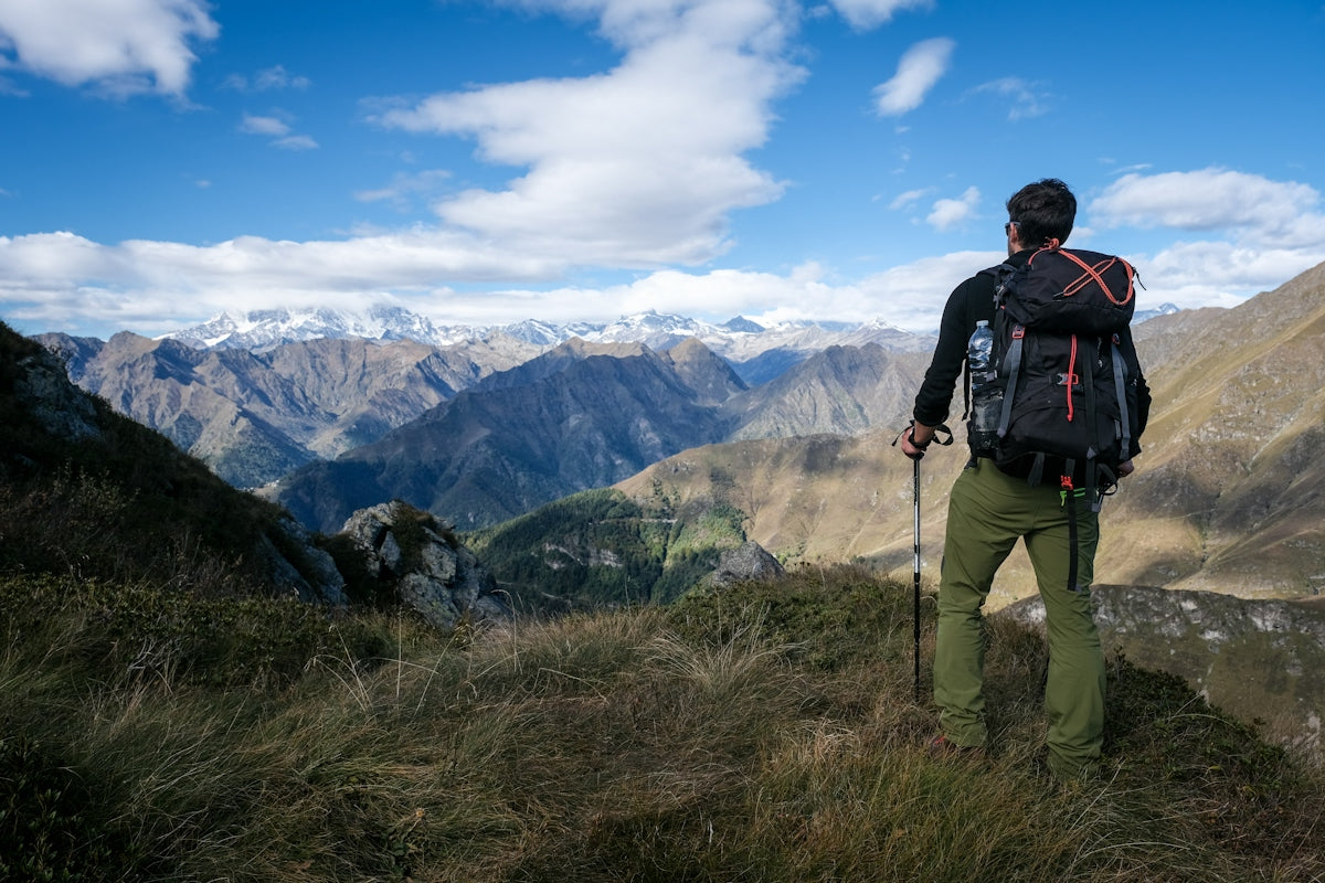 a man standing on top of a grass covered hillside