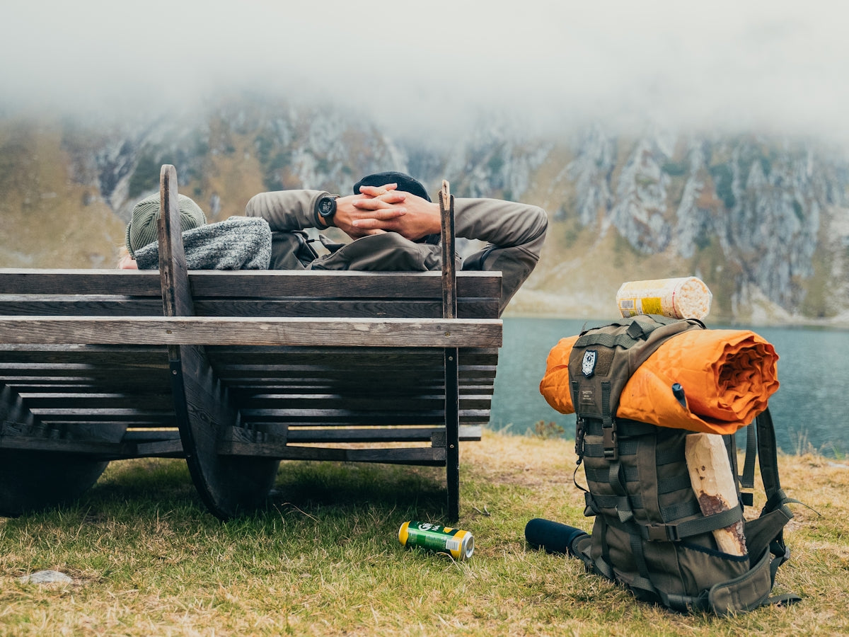 A man is sleeping on a bench with a backpack