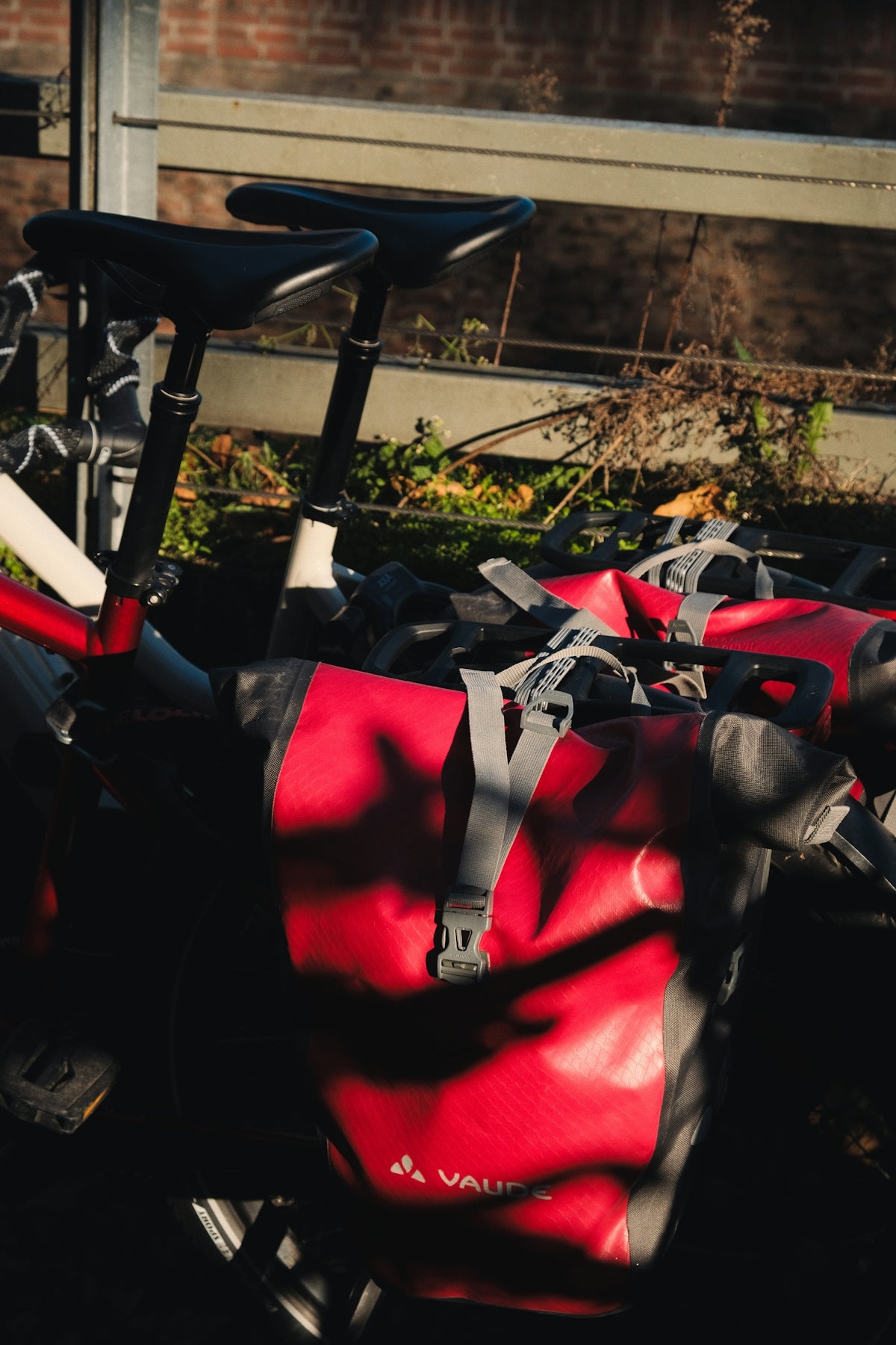 Two bicycles with red panniers parked outdoors