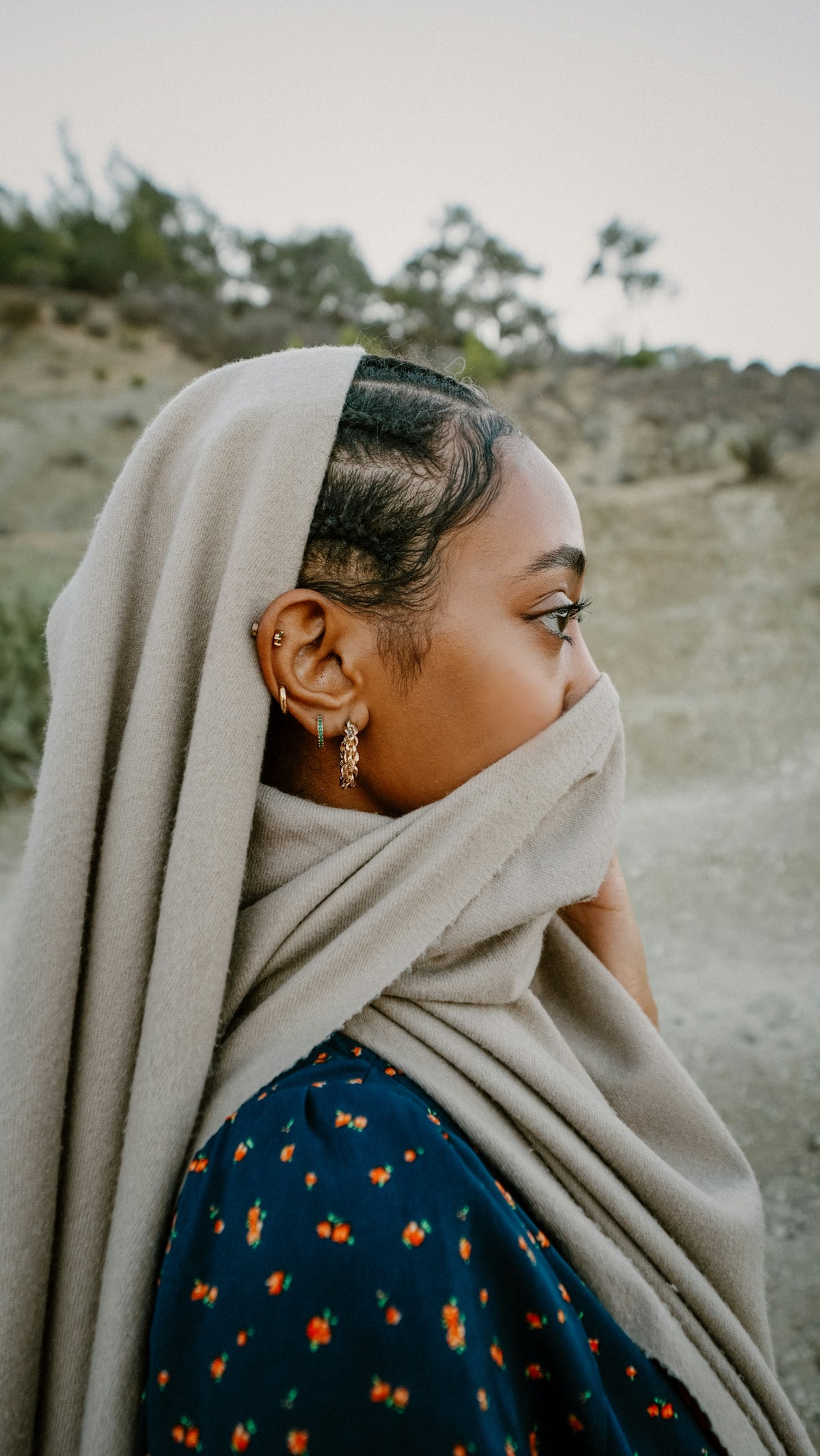 Woman with scarf covering mouth and nose outdoors.