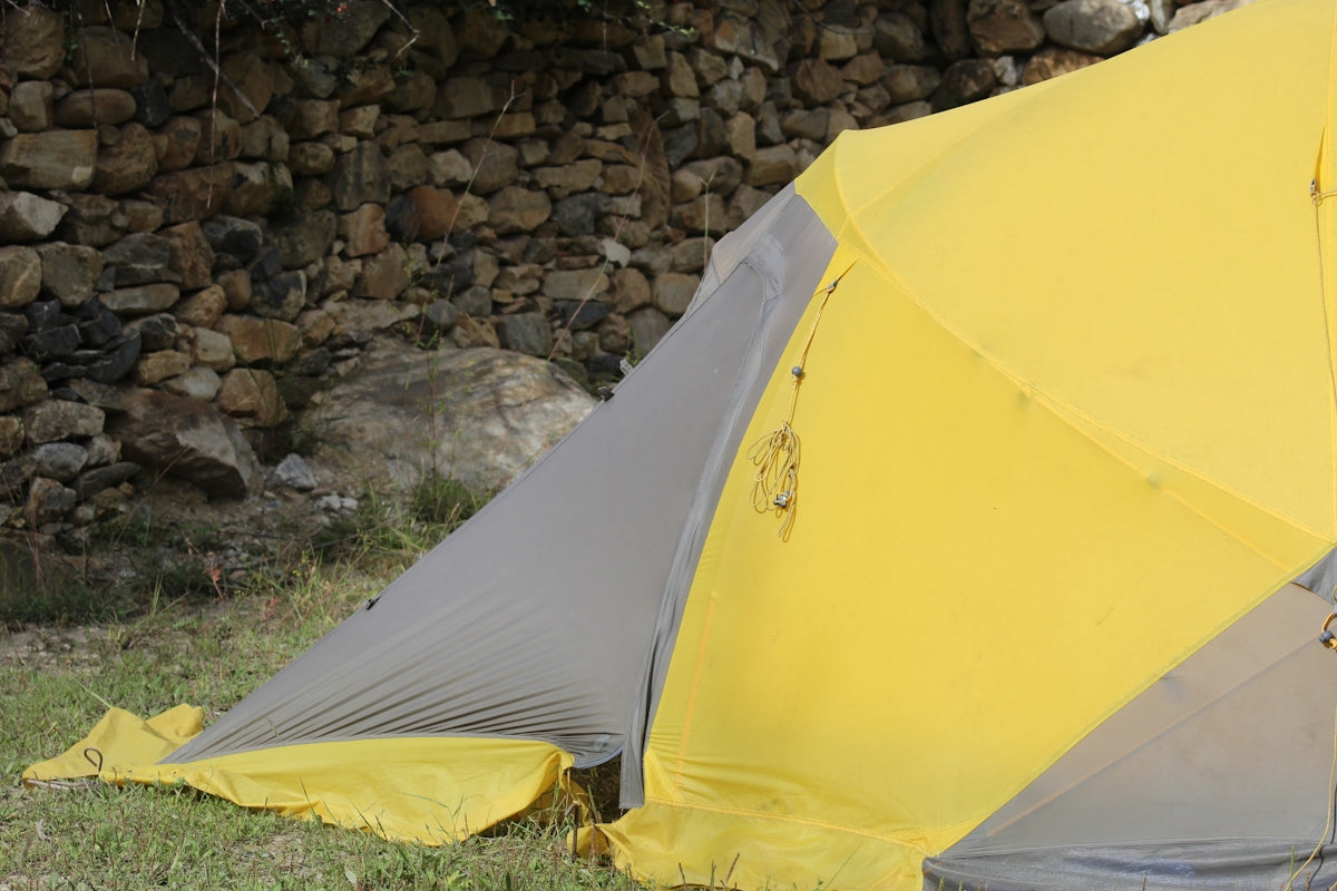 A yellow tent pitched on grassy ground
