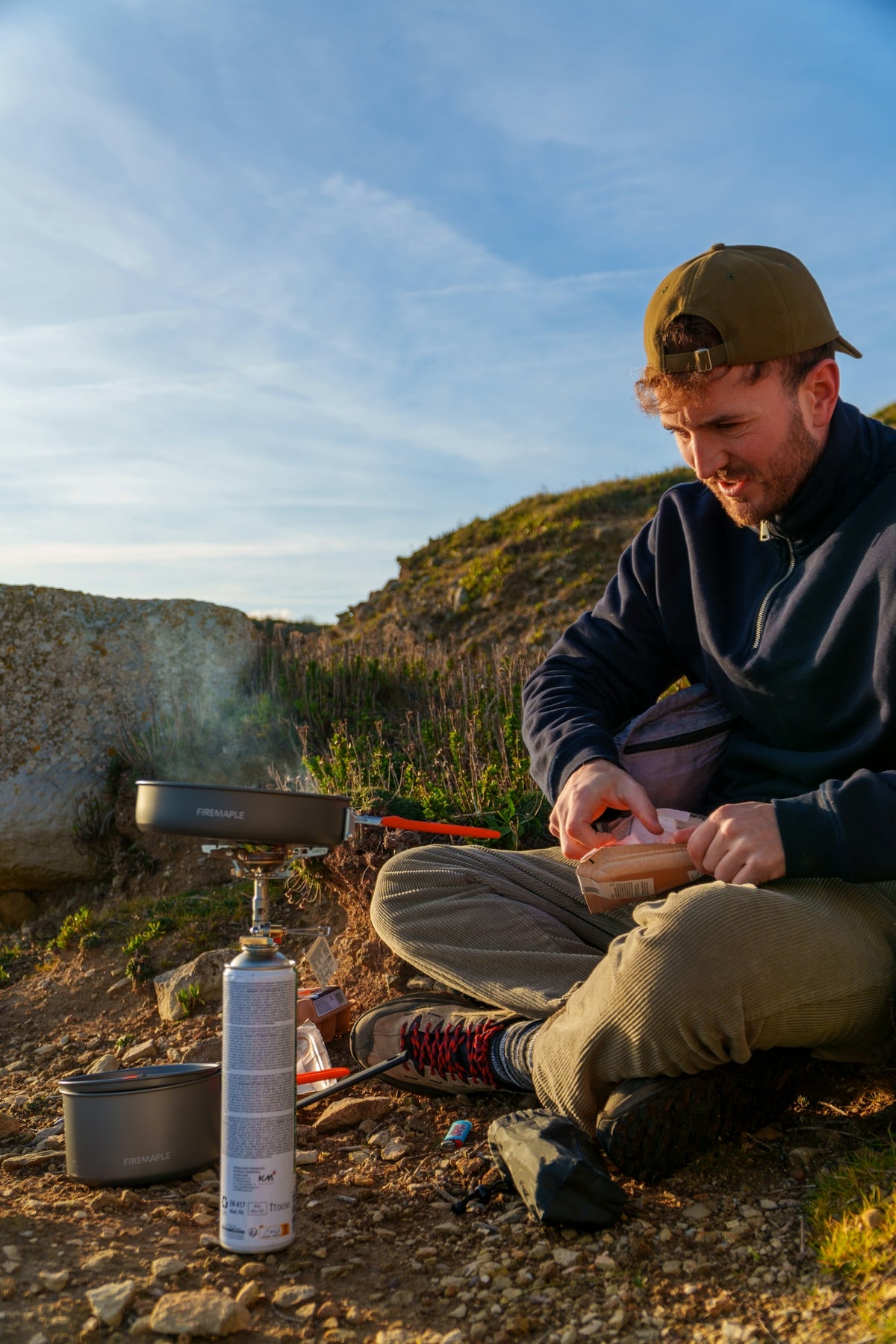 Man cooking outdoors on a camping stove.