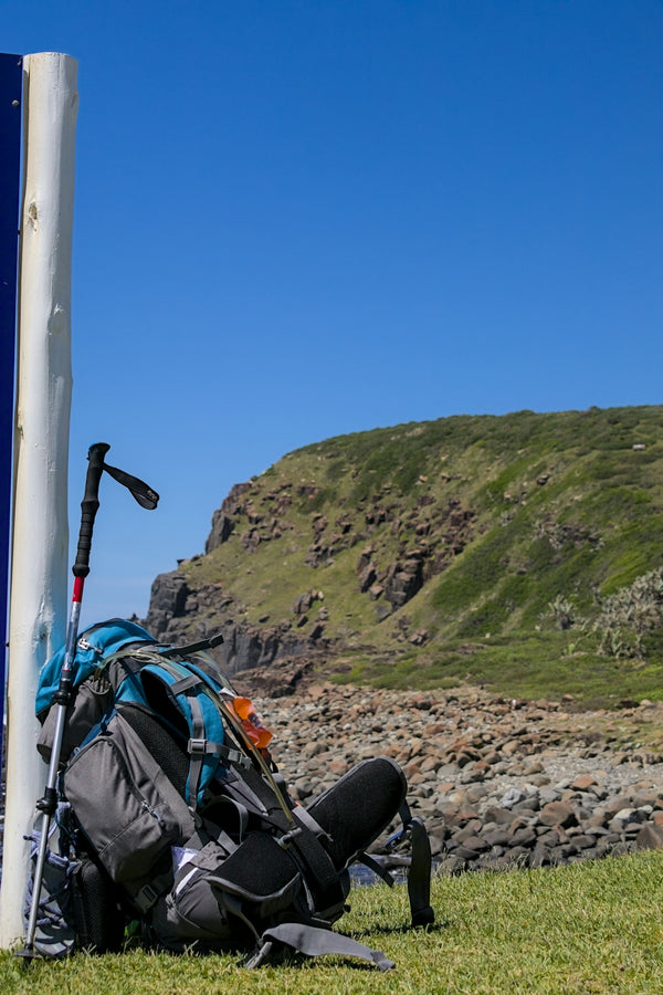 Backpack and hiking pole lean against a post