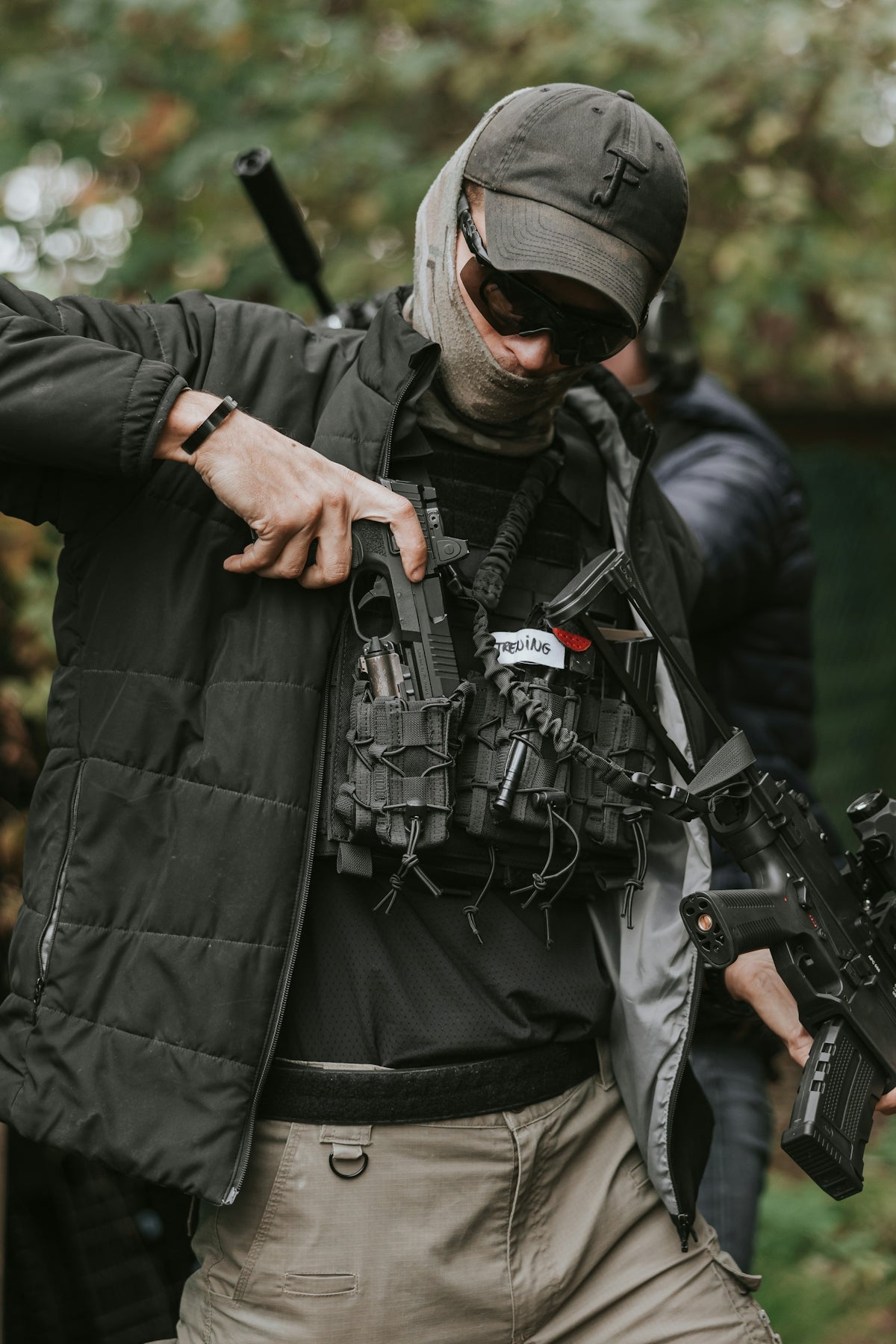 Man in tactical gear holstering a handgun.