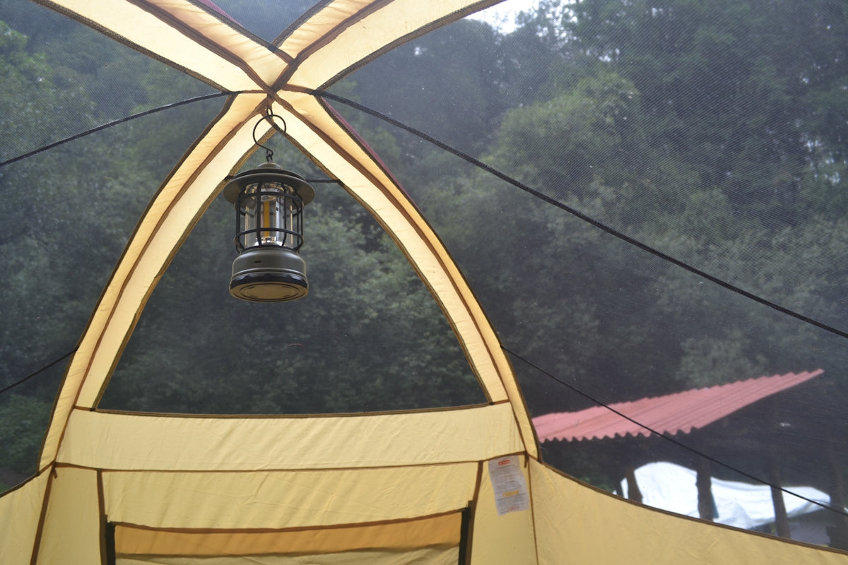 Lantern hanging inside a camping tent with trees outside