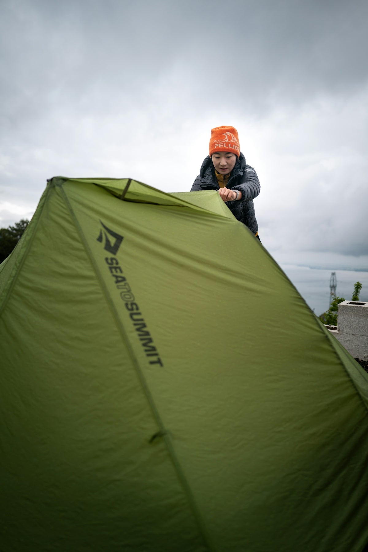 Person setting up a green tent outdoors